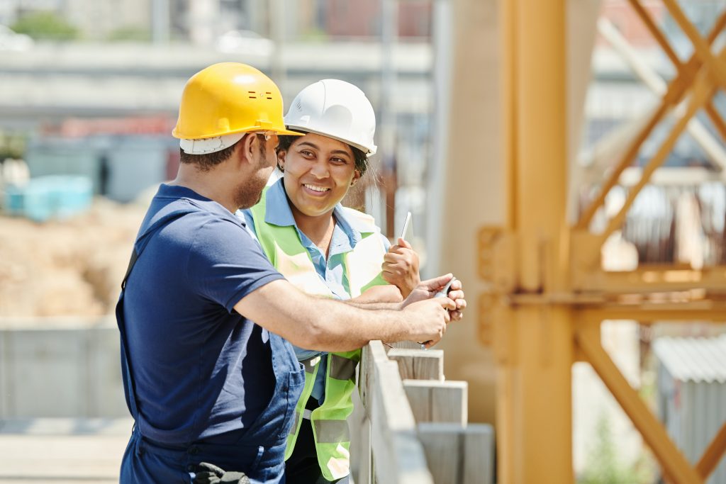 A photo of two construction workers talking on a construction site